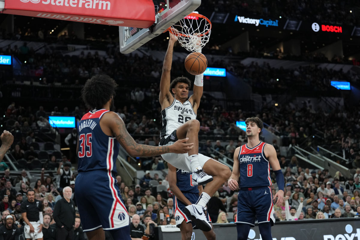 Jan 29, 2024; San Antonio, Texas, USA; San Antonio Spurs forward Dominick Barlow (26) dunks between Washington Wizards forwards Marvin Bagley III (35) and Deni Avdija (8) in the first half at Frost Bank Center.
